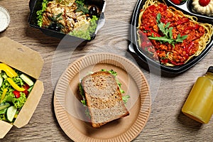 Lunchboxes with different meals on wooden table, flat lay. Healthy food delivery