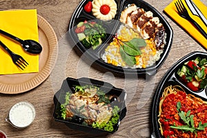 Lunchboxes with different meals on wooden table. Healthy food delivery
