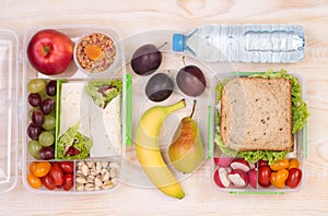 Lunchboxes with sandwiches, fruits, vegetables, and water
