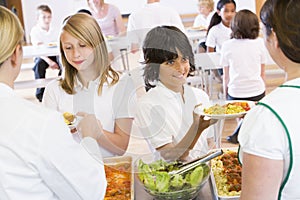 Lunchladies serving plates of lunch in a school