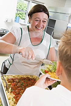 Lunchlady serving plate of lunch in a school