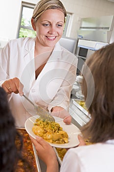 Lunchlady serving plate of lunch in a school