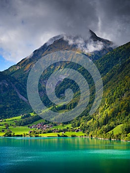 Lungern, canton of Obwalden, Switzerland. A view of rural homes in a green meadow. A lake in a mountain valley.