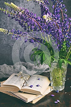 Lupine and old book. Still life with purple flowers bouquet in vase.