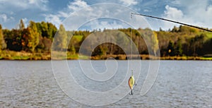 Lure fishing - spinning rod with bait on pond background. copy space