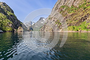 Lush cliffs and snowy peaks reflect in Trollfjorden\'s calm waters