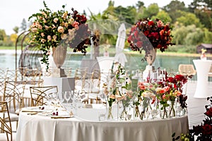 Lush decor with roses for the head table on the wedding day. Table decorated with flowers for outdoor wedding day