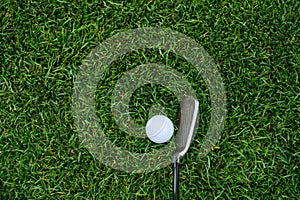 Lush green golf course grass in the rough, with a white golf ball and an iron clubhead ready to play