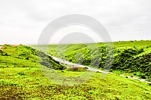 Lush green landscape, trees and foggy mountains in Ayn Khor tourist resort, Salalah, Oman