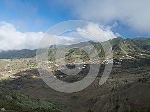 Lush green valley with terraced fields and village Las Portelas. Landscape with rocks and hills seen from hiking trail
