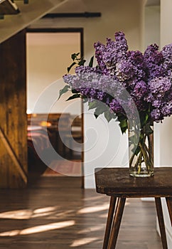 Lush lilac bouquet in a transparent glass vase in the interior