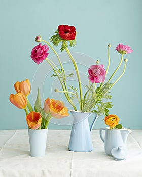 Lush natural light old Dutch Delft blue lidded vase with orange tulip  on  white linen against a blue background