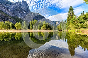 Trees and Sentinel Rock reflect in the smooth  Merced River in Yosemite national park