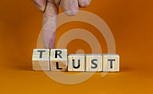 Lust or trust symbol. Businessman turns wooden cubes and changes the words `lust` to `trust`. Beautiful orange table, orange