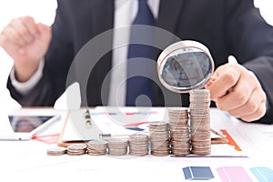 Lustful businessman with a magnifying glass in hand carefully observes a row of dollar coins