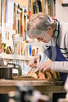 Luthier carefully carving the shape of a lute