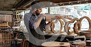 A luthier checks an hollow body guitar neck in his workshop to verify alignment, people arts and craft concept