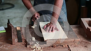 Luthier creating a guitar and using tools in a traditional