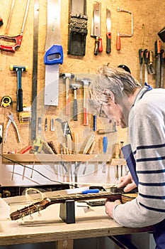 Luthier filing the frets of an acoustic guitar