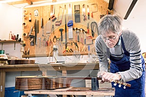 Luthier filing the frets of an acoustic guitar