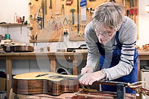 Luthier filing the frets of an acoustic guitar photo