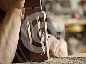 Luthier grinds the head of seven-string guitar.