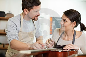 luthier and guitar maker apprentice work on acoustic guitar