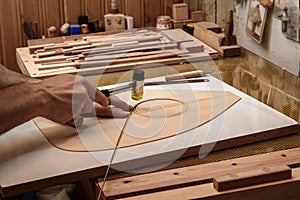 A luthier - instrument maker - inlaying ebony wood strips on the surface of soundboard to give point to whole outlines