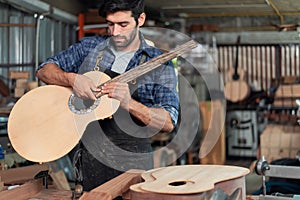 Luthier making wooden musical and using traditional tools in workroom with manual tools