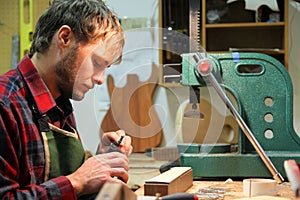 Luthier Woodworker Building Guitar in Workshop photo