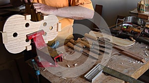 Luthier working with a chisel in a new violin or viola in the workplace