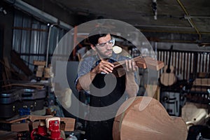 Luthier is working on the neck of a classical guitar