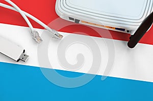 Luxembourg flag depicted on table with internet rj45 cable, wireless usb wifi adapter and router. Internet connection concept