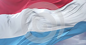 Luxembourg flag waving at wind with blue sky in slow, loop