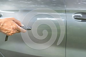 A luxurious car owner stretching hand to use a key remote control to lock and unlock his car, a photo of selective focus with