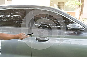 A luxurious car owner using a smartphone to lock, unlock and start car engine, a photo of selective focus with concept of high