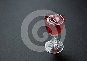 Luxurious cocktail in a crystal goblet with waves of drops on a dark stone background