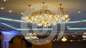 Luxurious crystal chandelier on the ceiling. Bottom view. Close-up. Huge crystal gold chandelier with candles.