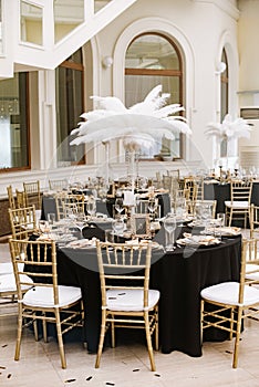 The luxurious design of the wedding celebration in the restaurant with large white feathers, stylish chairs