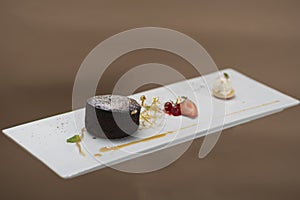 Luxurious dessert with brownie,  vanilla ice-cream placed on a macaron,  strawberries,  mint,  decorated with gold leafs and