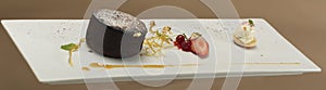 Luxurious dessert with brownie,  vanilla ice-cream placed on a macaron,  strawberries,  mint,  decorated with gold leafs and