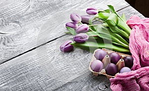 Luxurious fresh fashionable purple tulips on a wooden background next to Easter eggs