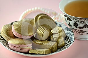 Luxurious gold French macarons and chocolates on a porcelain plate