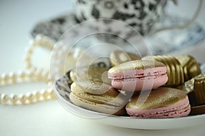 Luxurious gold French macarons and chocolates on a porcelain plate
