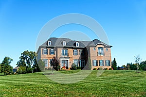 Luxurious large single family brick house with large green lawn. Landscape on a summer sunny day