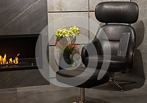 Luxurious living room with leather armchair, modern gas fireplace and flowers in a vase