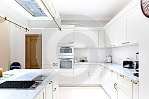 Luxurious modern kitchen. White cabinets of wooden furniture in home decoration. Appliances, sink and kitchen island