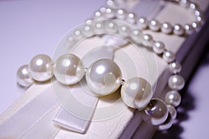 Luxurious pearl jewelry on a pink box. Snow-white pearls. Bijouterie. Jewelry. Snow-white beads on a white background. Brilliant
