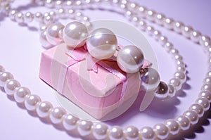 Luxurious pearl jewelry on a pink box. Snow-white pearls. Bijouterie. Jewelry. Snow-white beads on a white background. Brilliant p