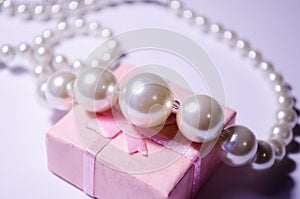 Luxurious pearl jewelry on a pink box. Snow-white pearls. Bijouterie. Jewelry. Snow-white beads on a white background. Brilliant p